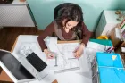 Architektka przy biurku w pracowni pracująca nad projektem domu z rysunkami i dokumentacją